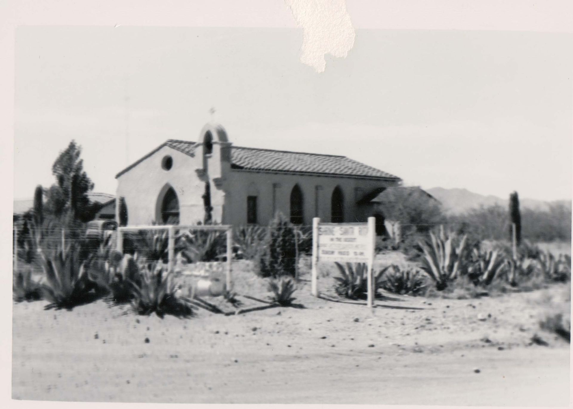 A black and white photo of a church in the desert