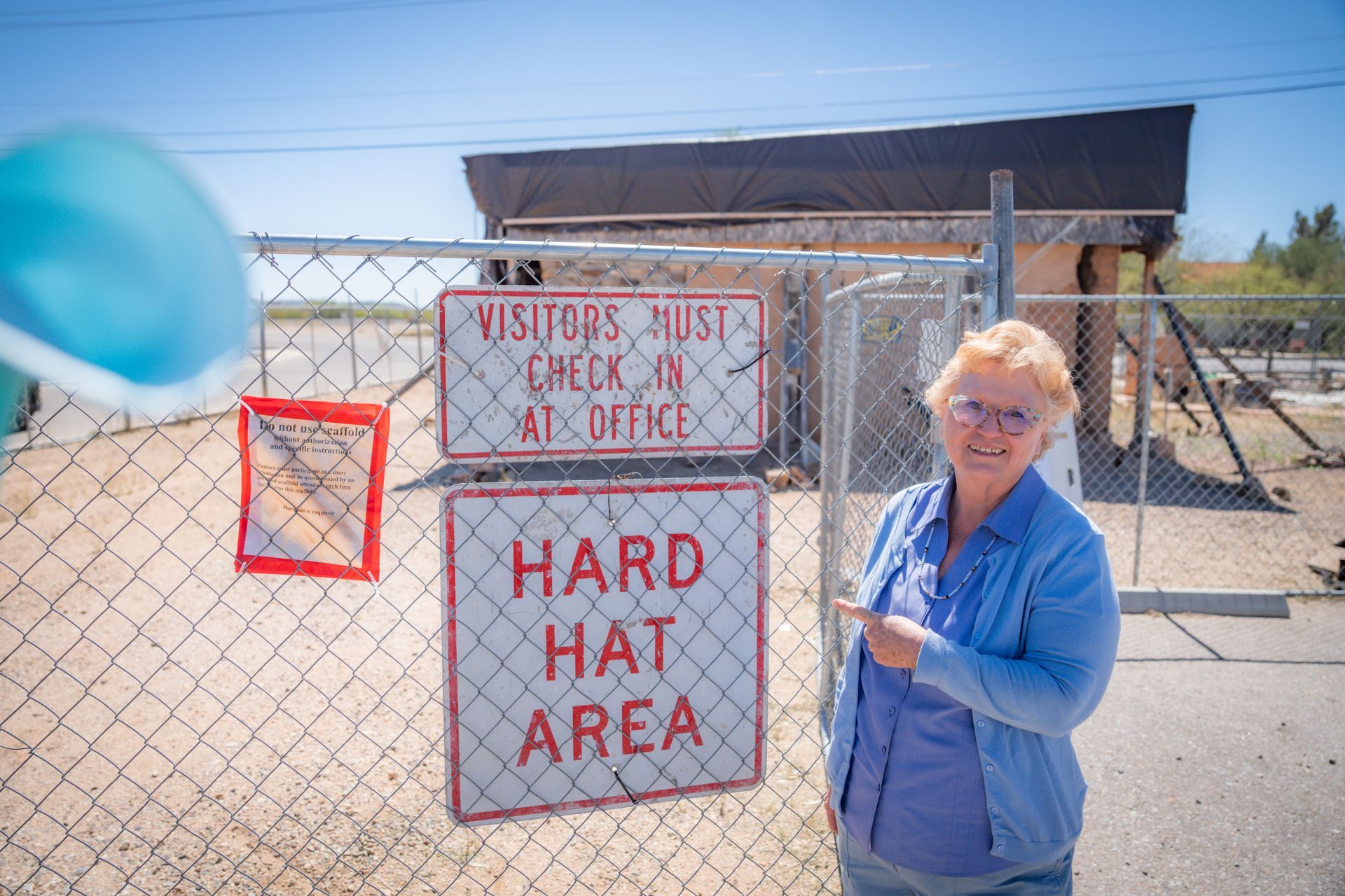 A woman is standing in front of a sign that says hard hat area
