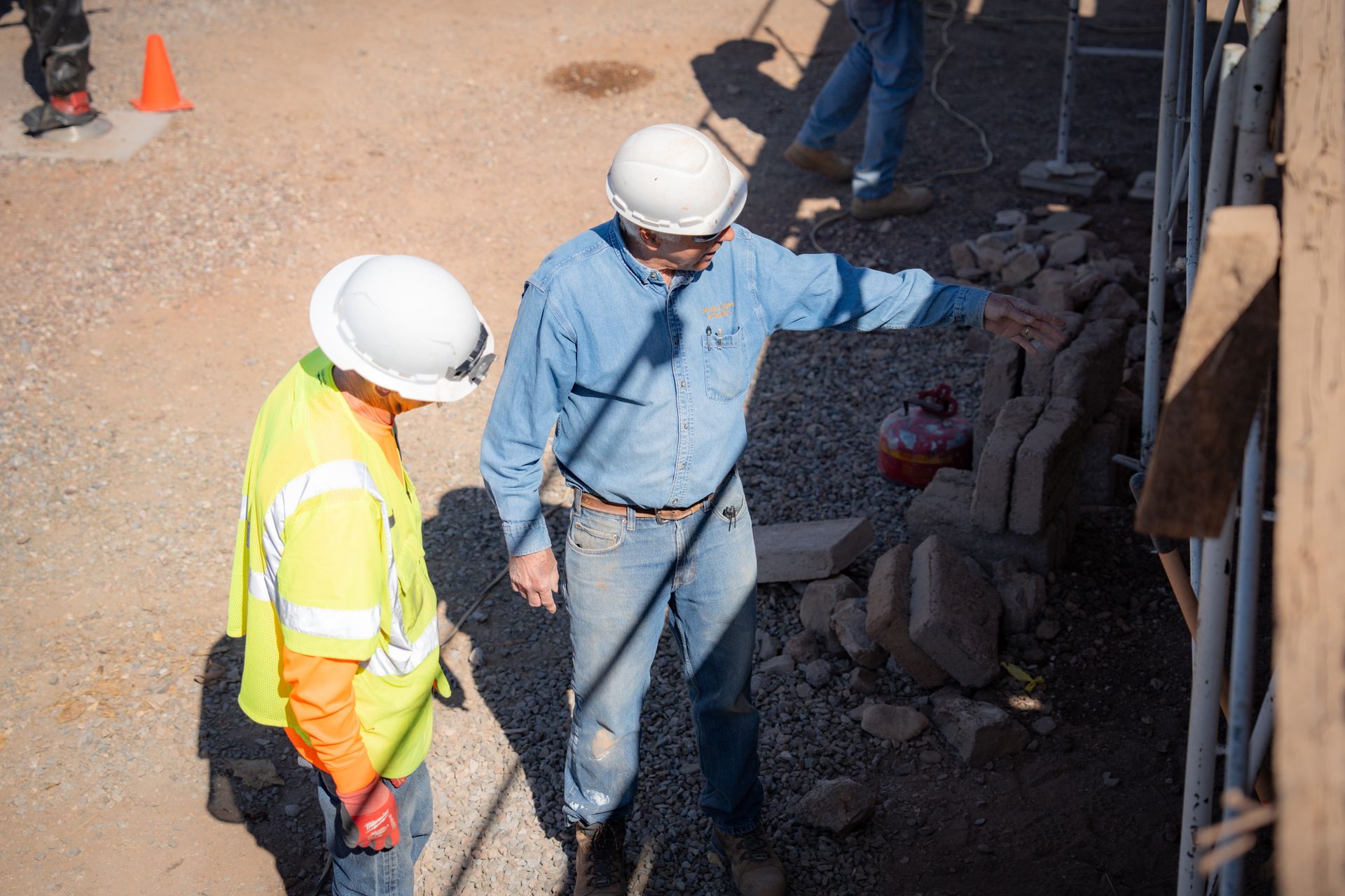 Two construction workers are standing next to each other on a construction site.