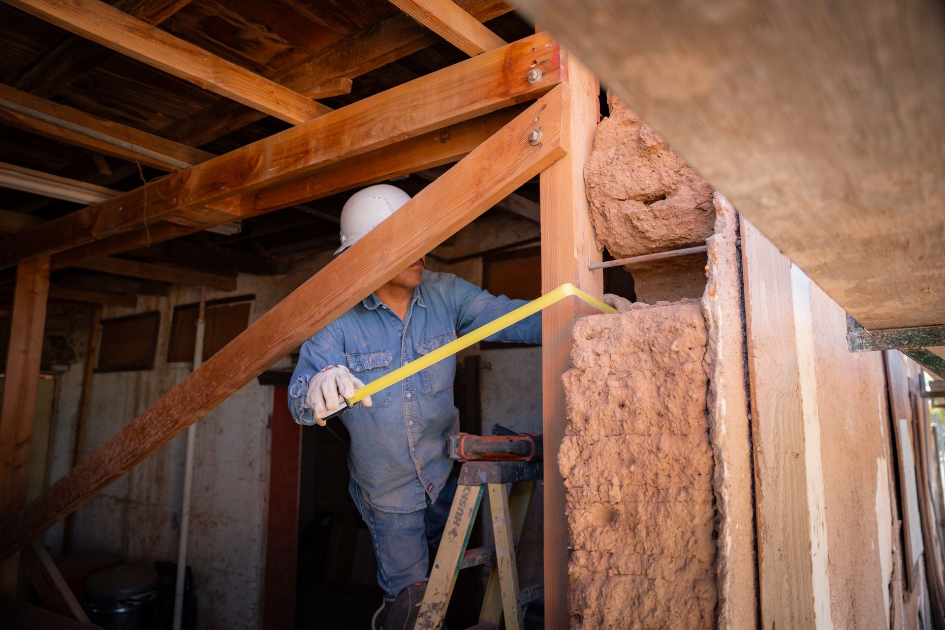 A man is measuring a wooden structure with a tape measure.