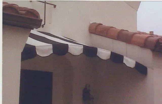 A white pergola with purple flowers hanging from it