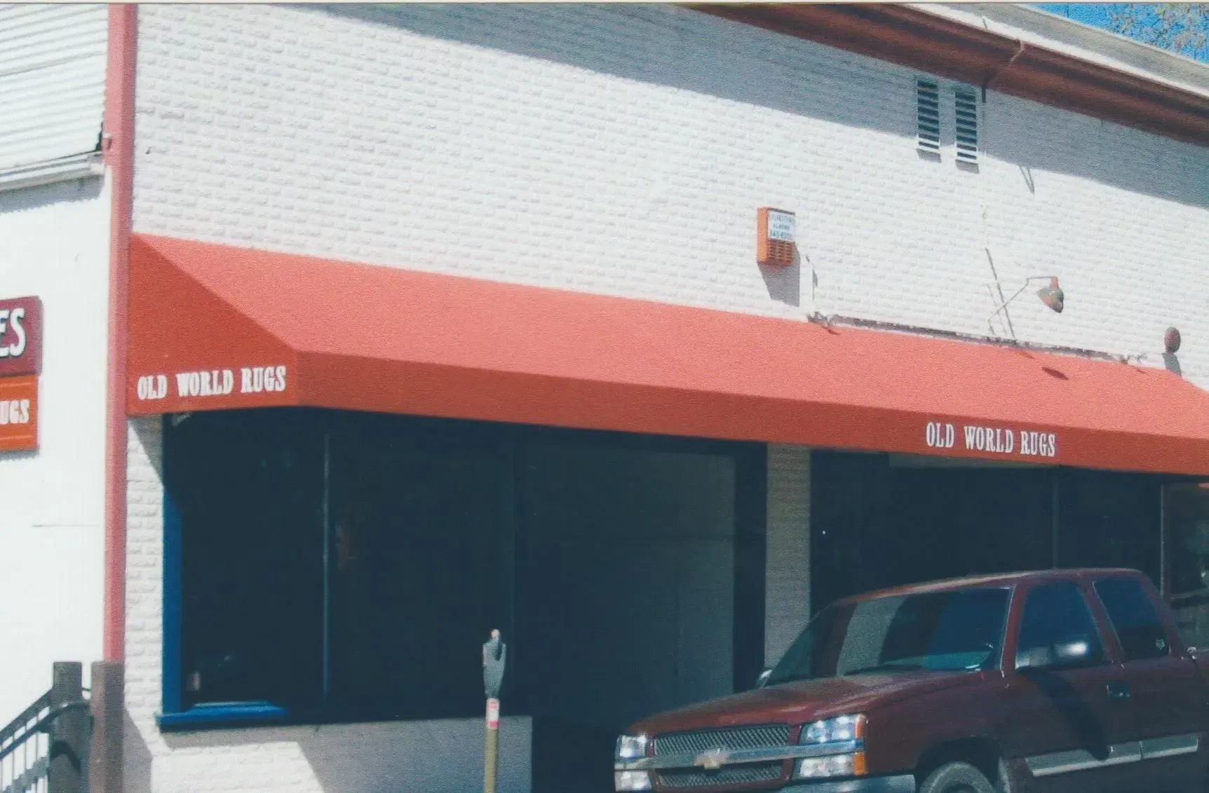 A red truck is parked in front of a building with a red awning