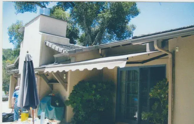 A picture of a house with an awning and umbrella