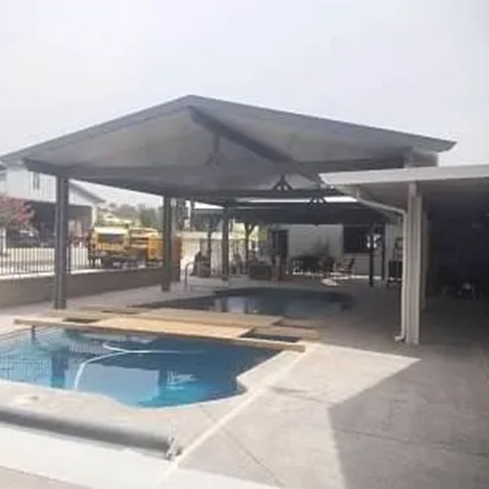 There is a swimming pool in the backyard with a canopy over it. There is a swimming pool in the backyard with a canopy over it.