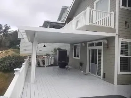A large white deck with a covered patio in front of a house.