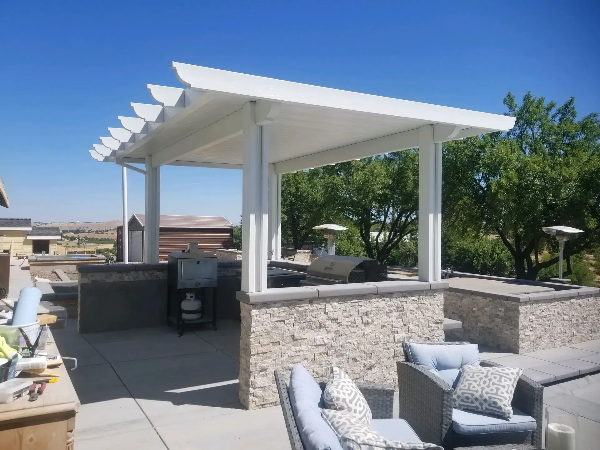 A patio with a couch and a coffee table under a pergola.