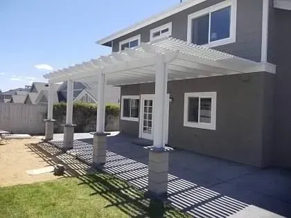 A house with a pergola and a patio in front of it.