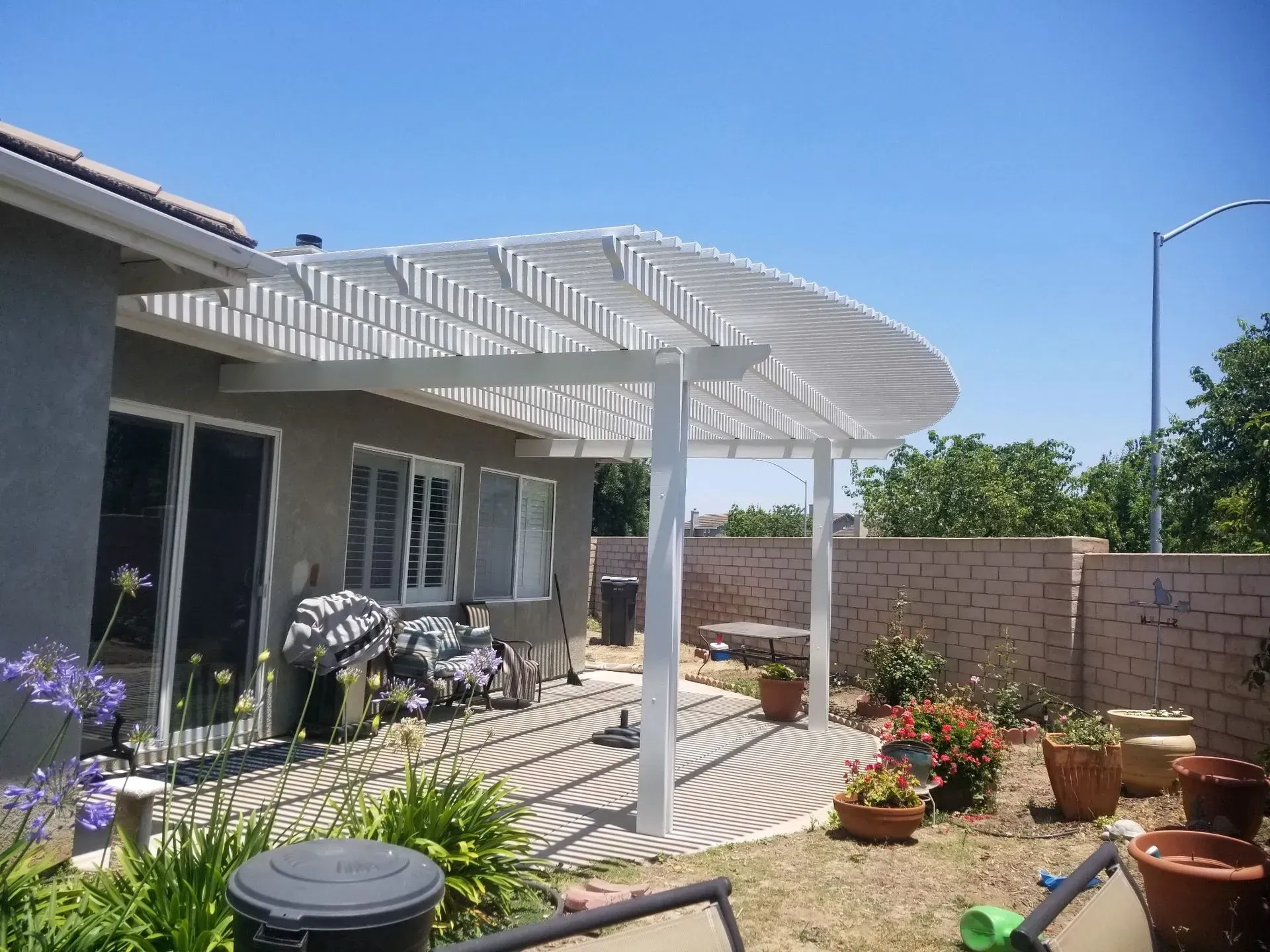 A white pergola is in the backyard of a house