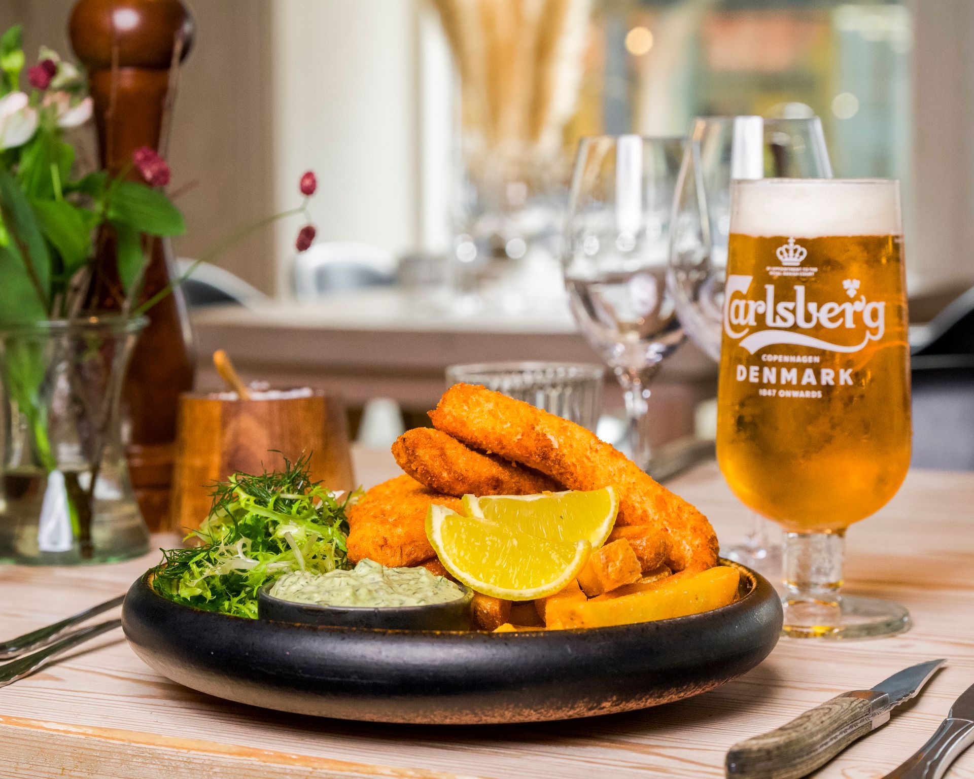 Fish and chips med øl ved et restaurantbord.