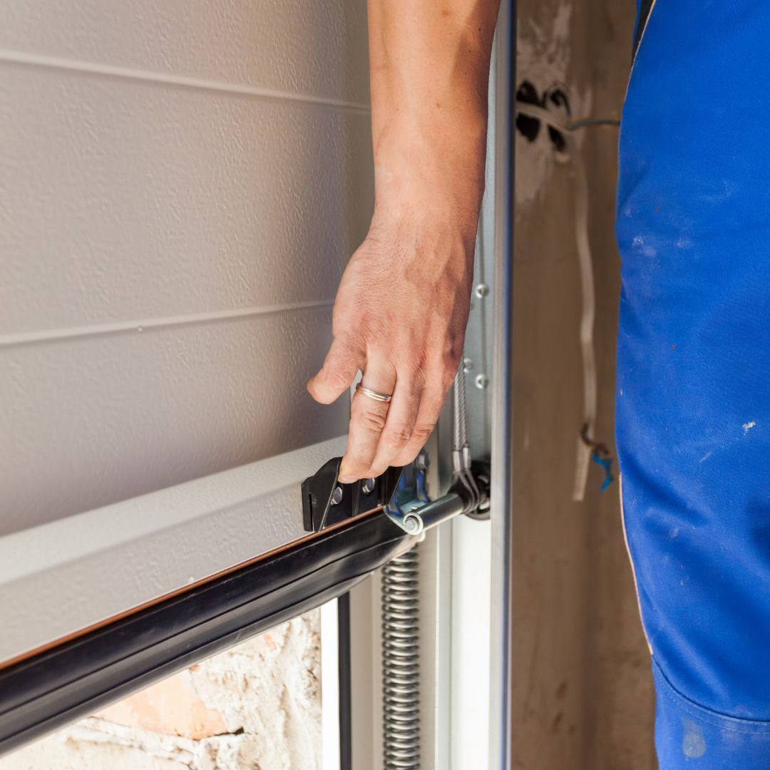 A trained garage door repairman working on a garage door