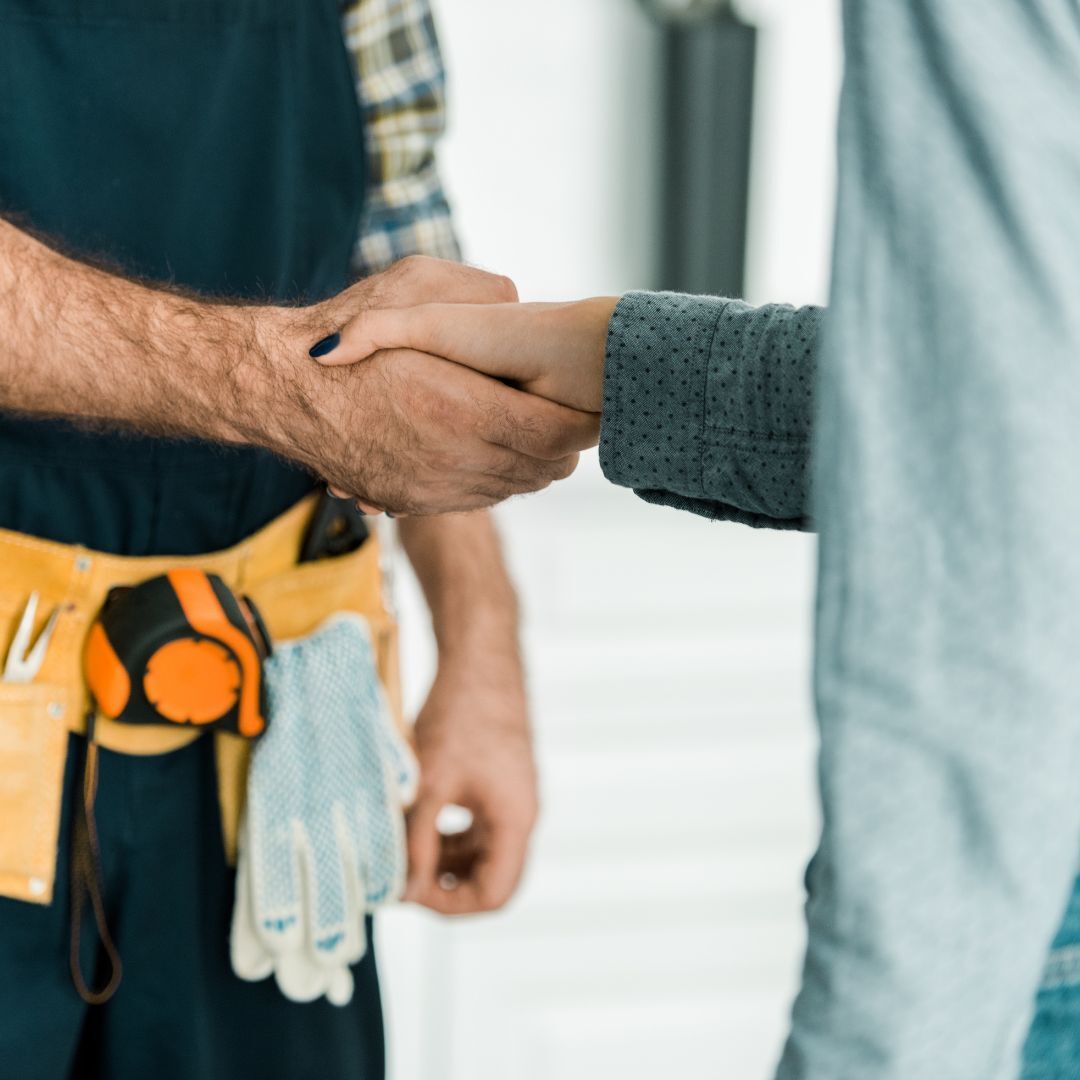 A woman shaking hands with a repairman