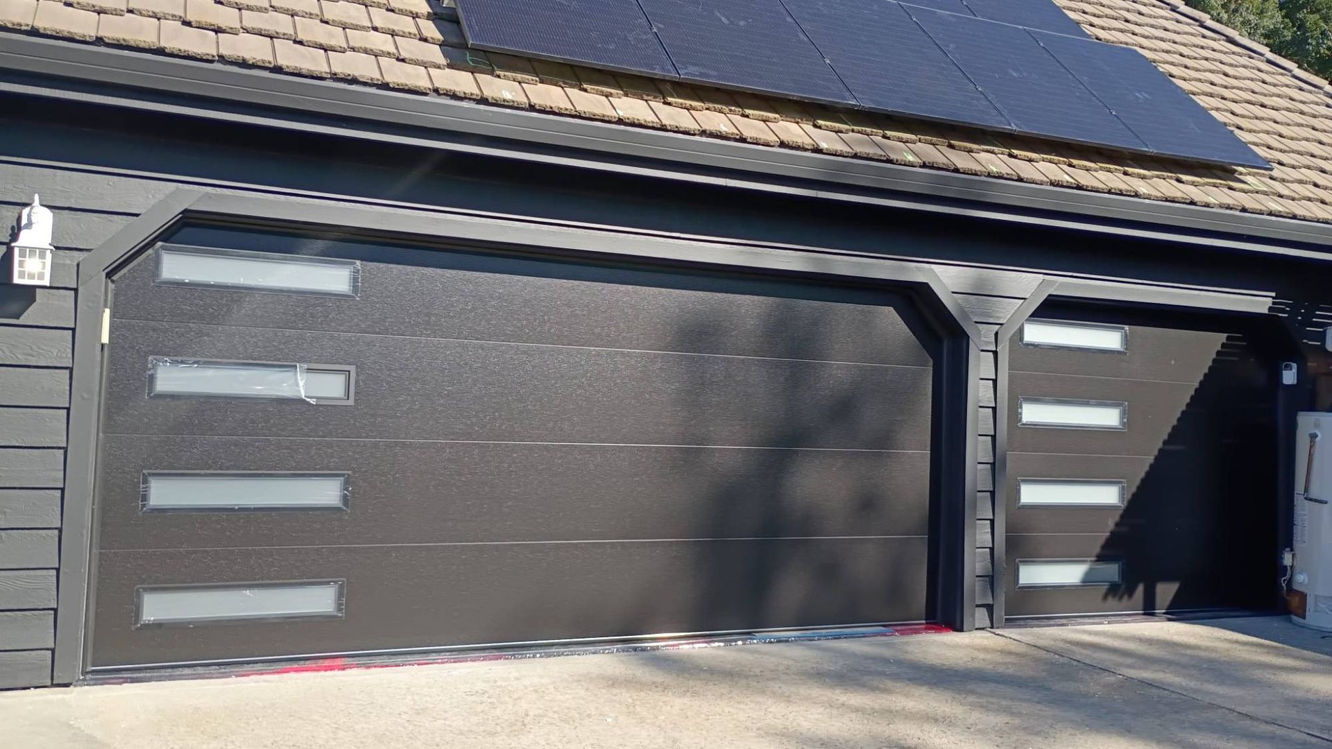 Two dark brown modern garage doors with frosted horizontal window strips, fully closed