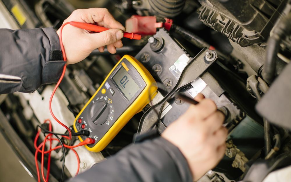 A Person Is Using A Multimeter To Test A Car Battery — Gillies Enterprises Pty Ltd In Narrabri, NSW