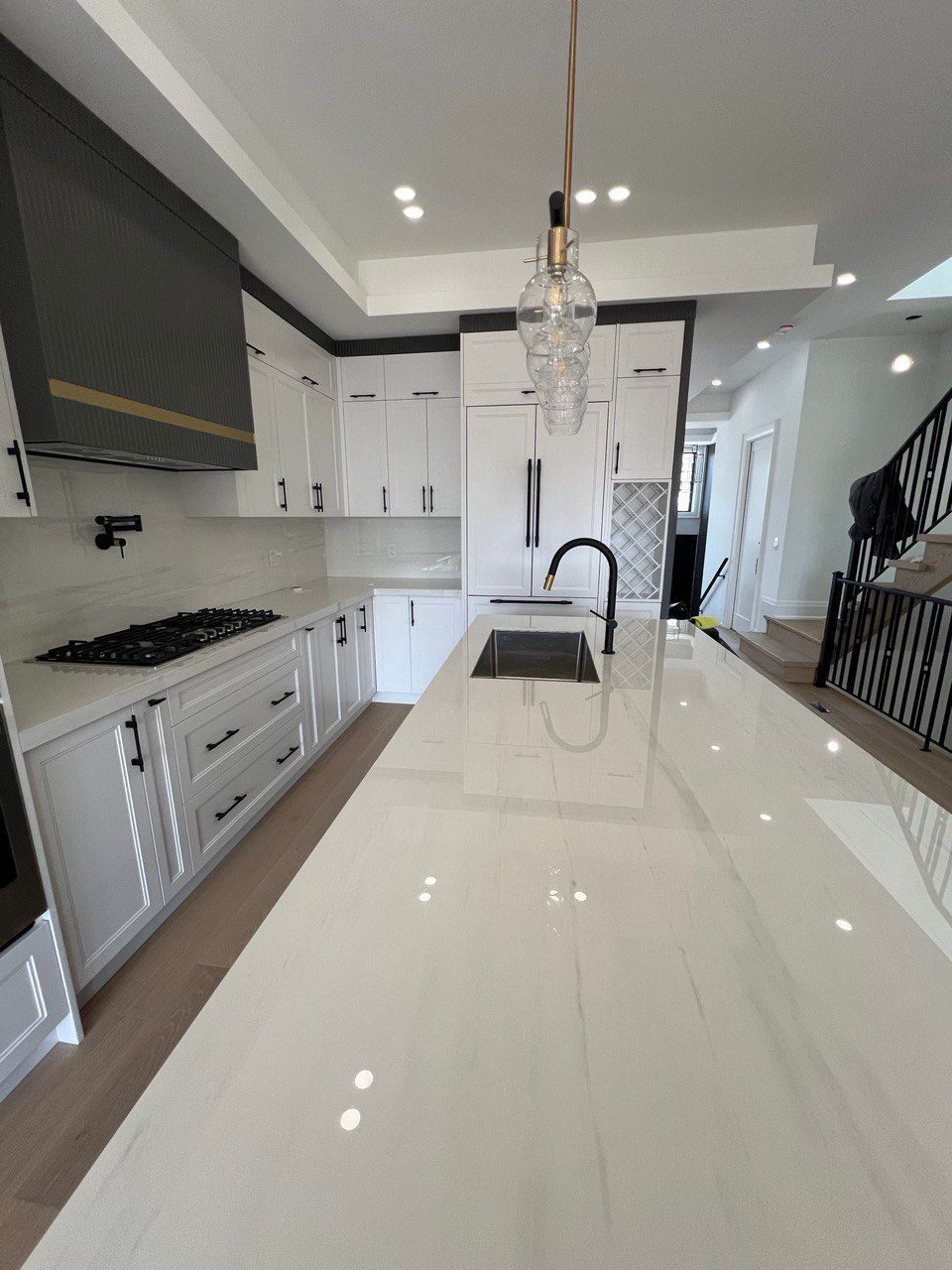A kitchen with white cabinets and a large island with a sink.