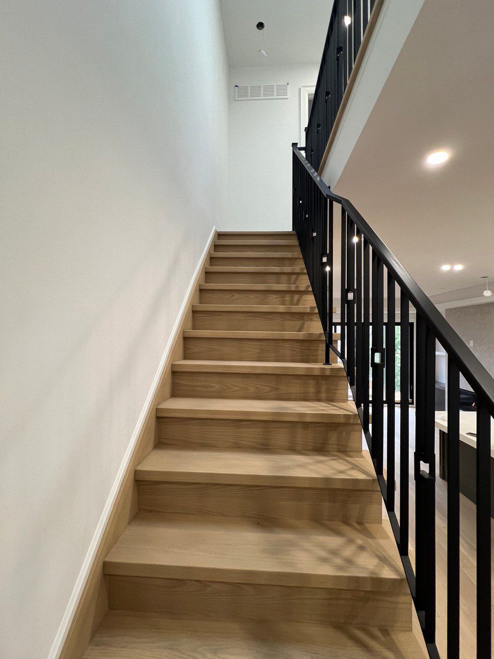 A staircase with wooden steps and a black railing in a house.