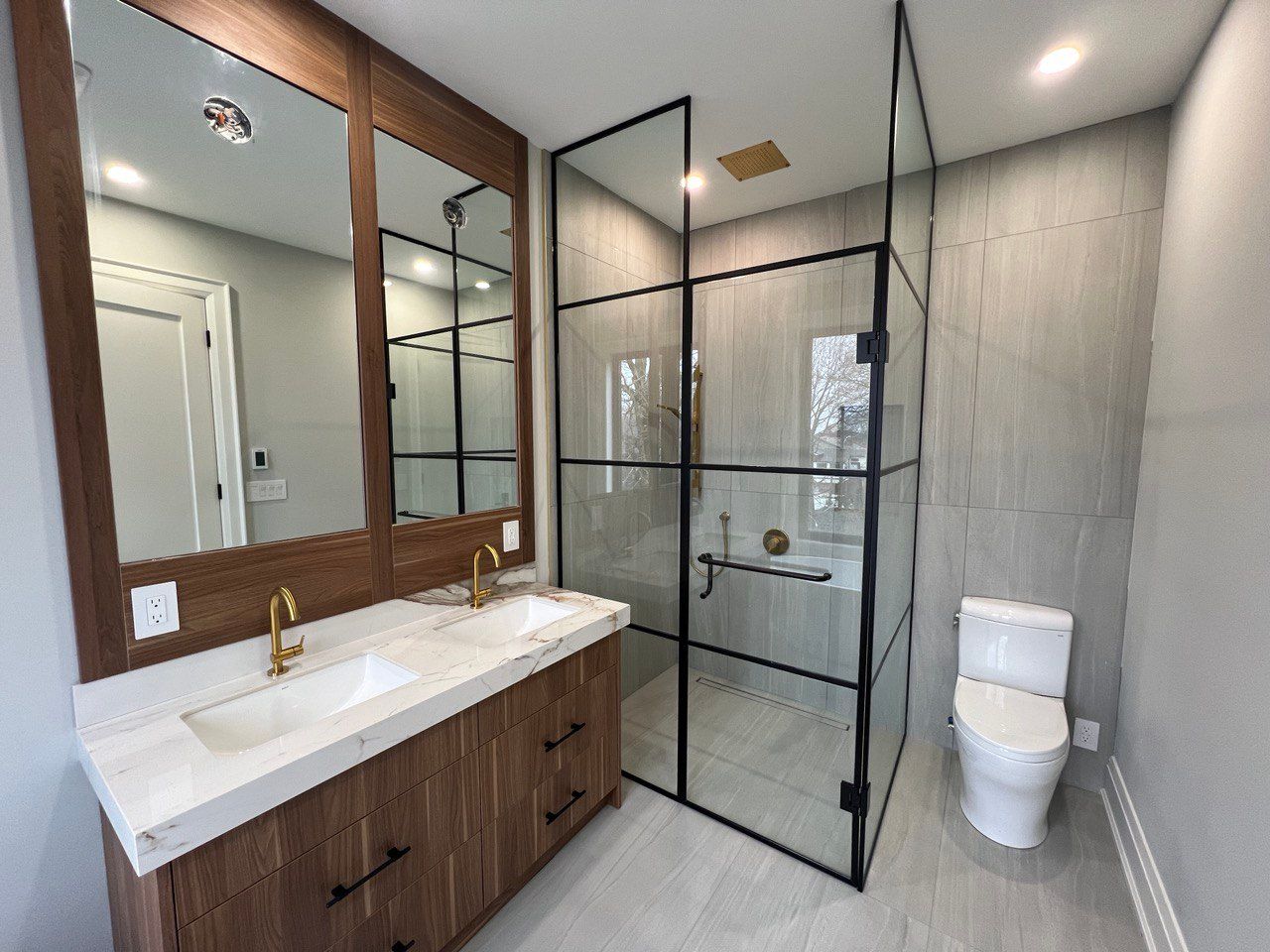 A bathroom with two sinks , a toilet , and a walk in shower.