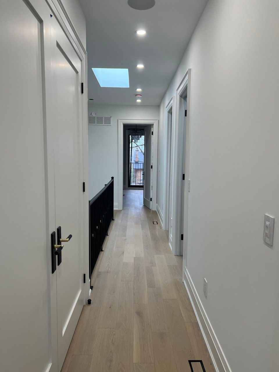 A long hallway with hardwood floors and white walls