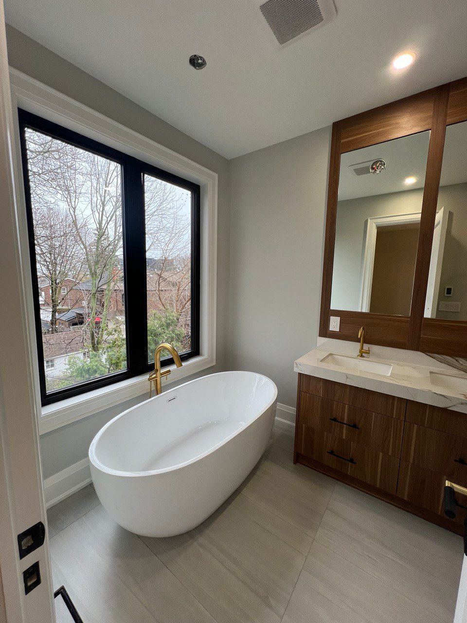 A bathroom with a tub , sink , mirror and window.