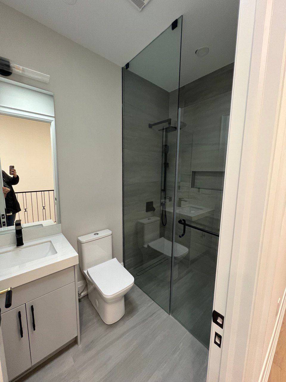 A bathroom with a toilet , sink , mirror and walk in shower.