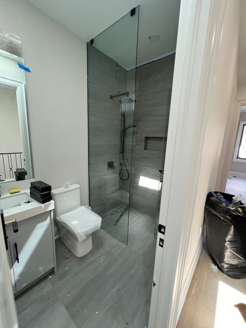 A bathroom with a toilet , sink , mirror and walk in shower.