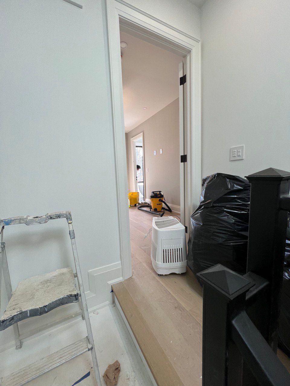 A room with a ladder and a vacuum cleaner in it.