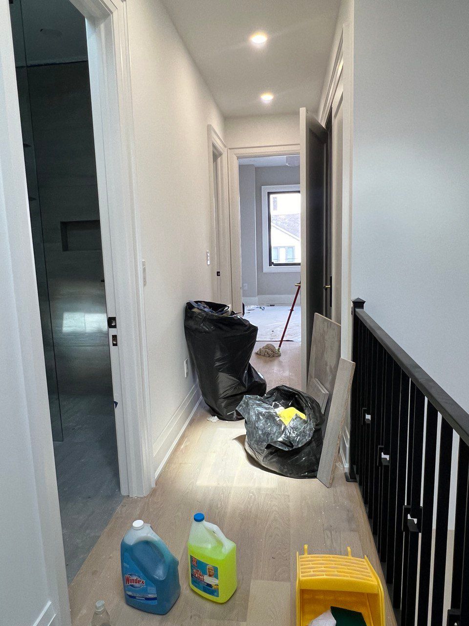 A hallway with bottles of cleaning supplies on the floor.