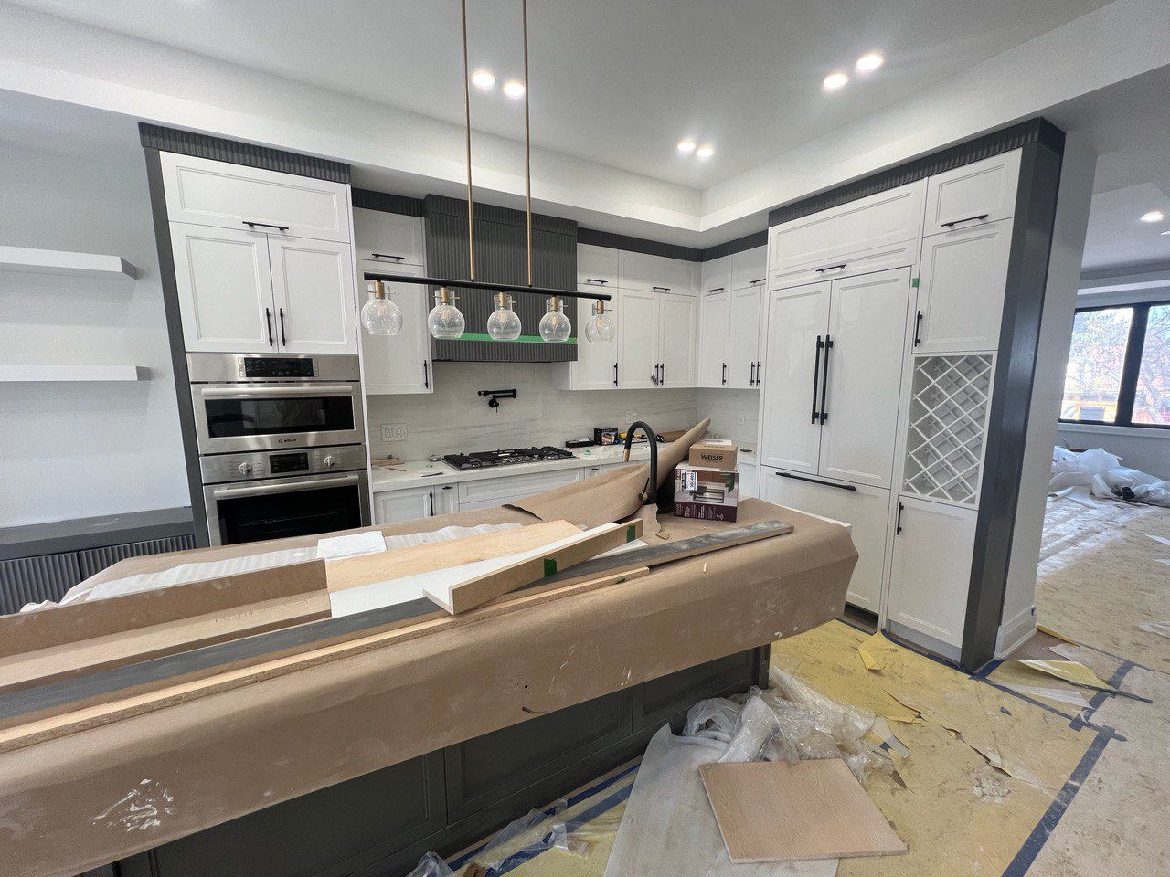 A kitchen under construction with white cabinets and stainless steel appliances.