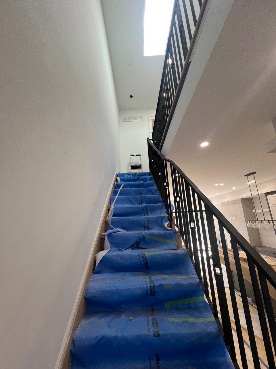 A set of stairs with blue carpet and a black railing.