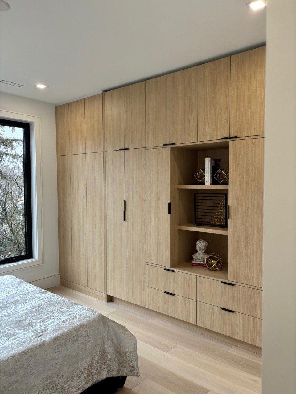 A bedroom with a bed and lots of wooden cabinets and drawers.