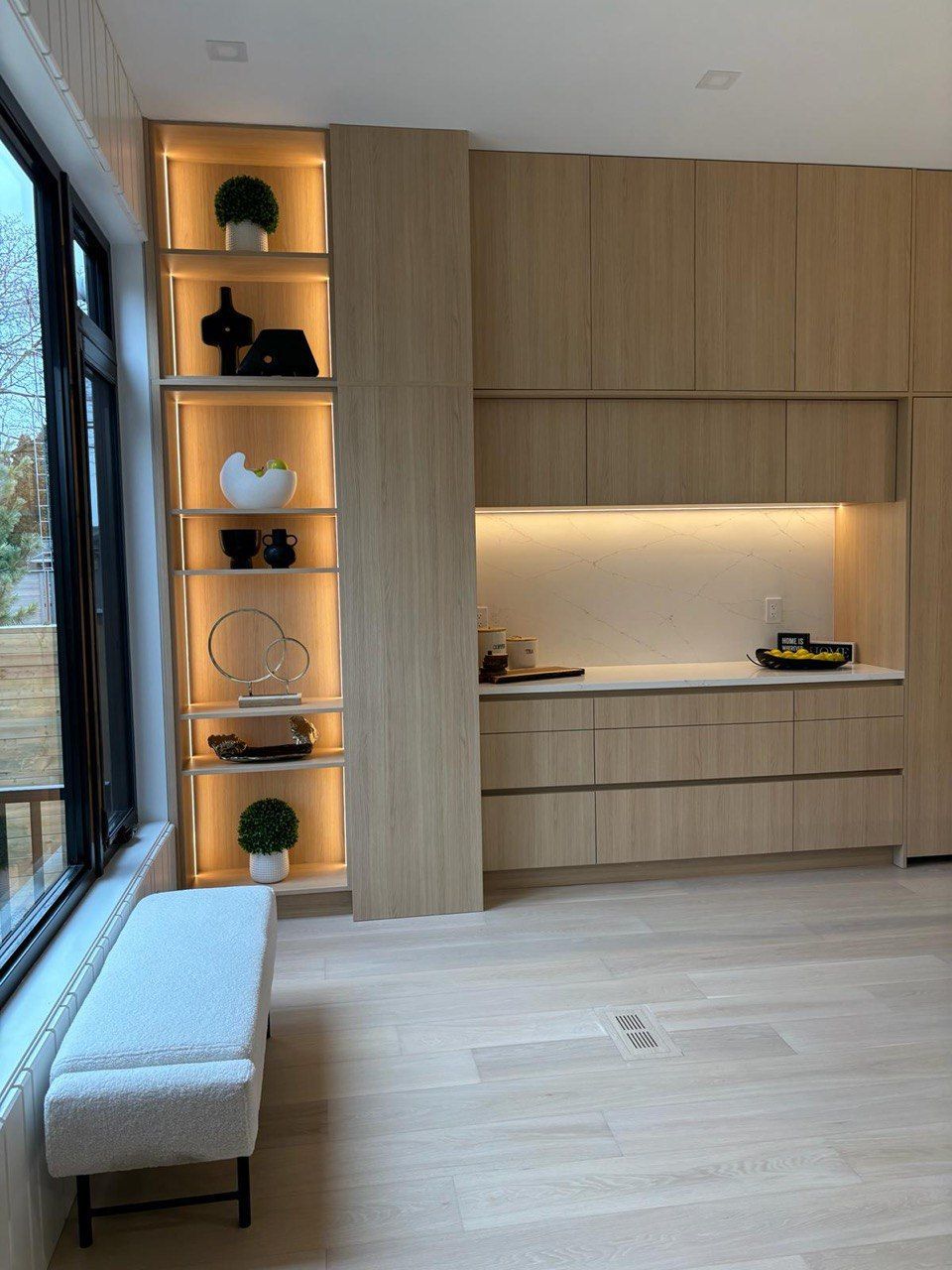 A kitchen with wooden cabinets and a bench in front of a window