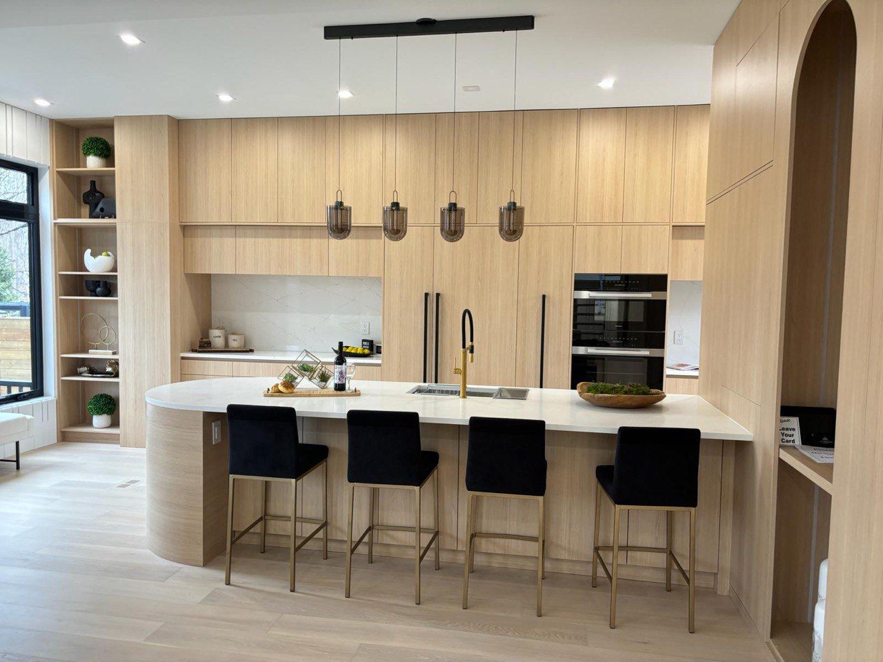 A kitchen with wooden cabinets and stools and a large island.