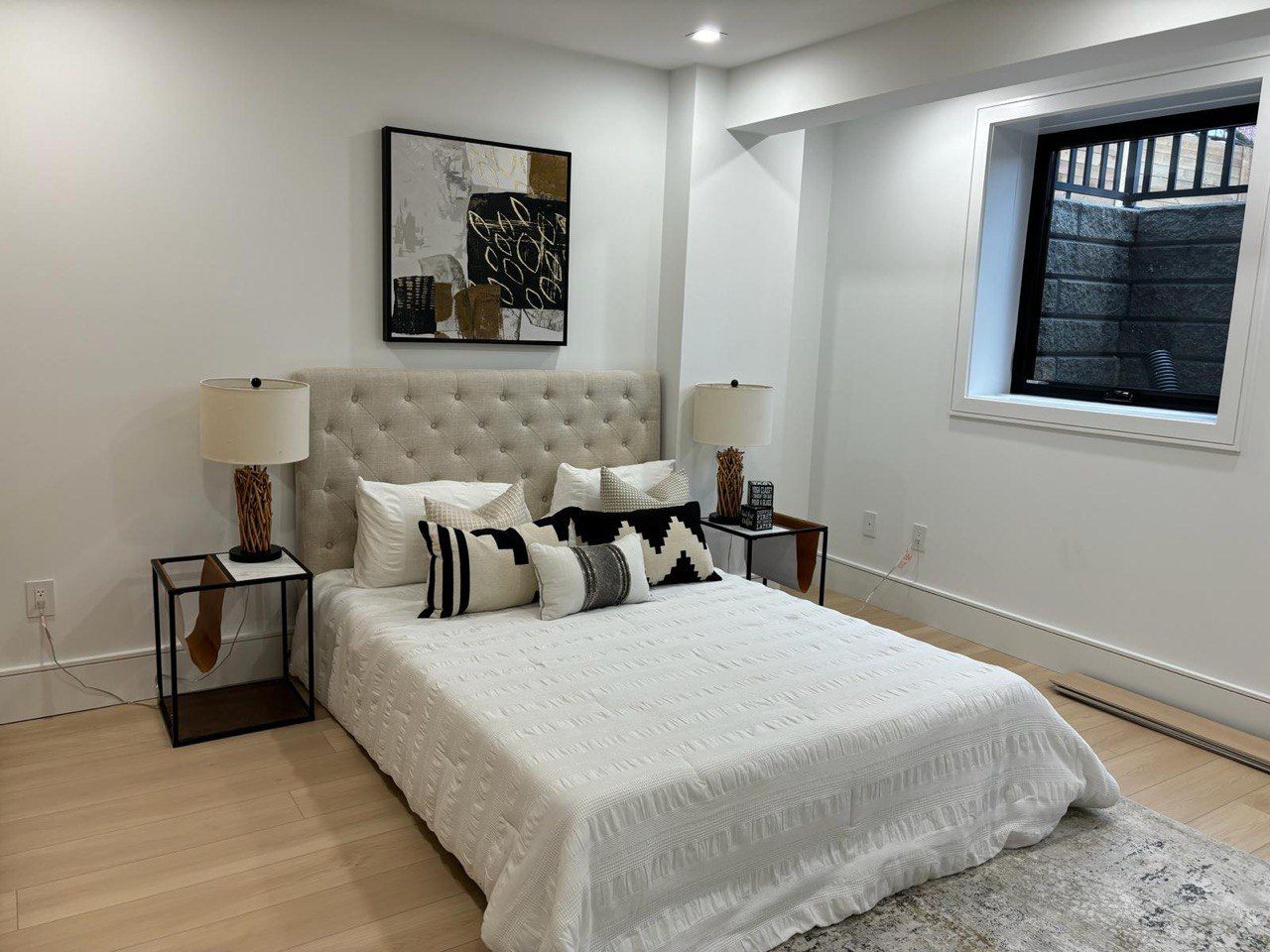 A bedroom with a bed , nightstands , lamps and a window.