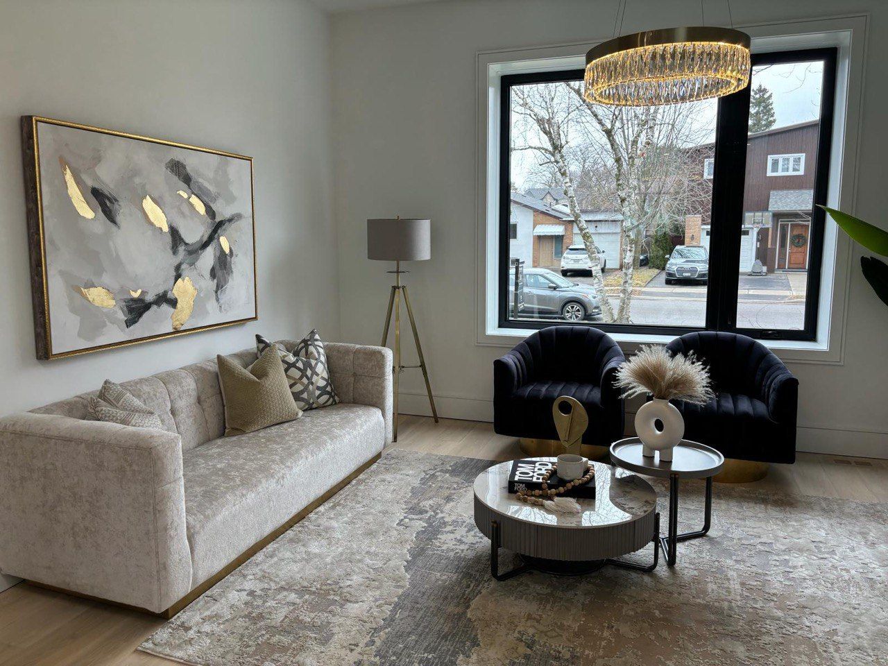 A living room with a couch , two chairs , a coffee table and a large window.