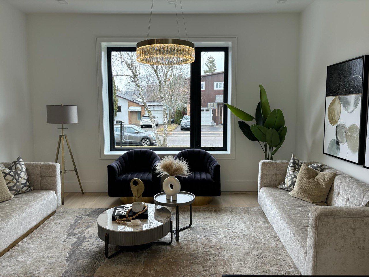 A living room with two couches , two chairs , a coffee table and a large window.