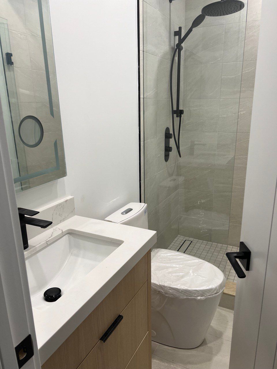 A bathroom with a toilet , sink and shower.