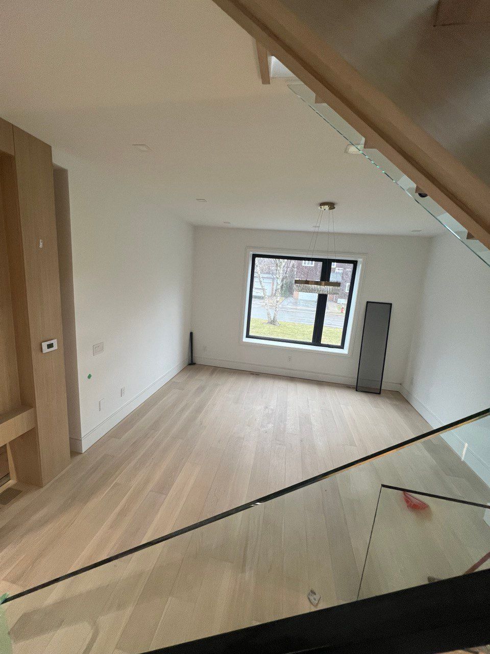 An empty room with a large window and a glass railing