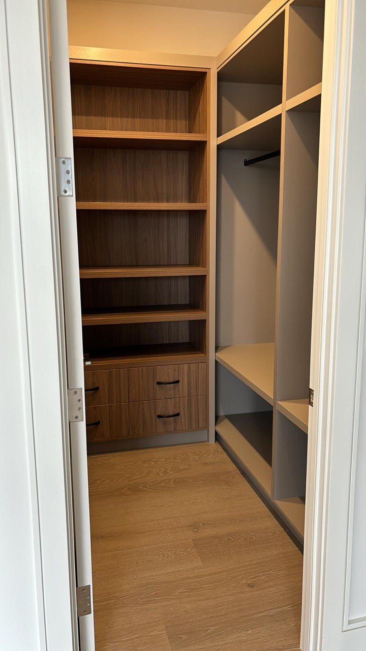 A walk in closet with lots of shelves and drawers.