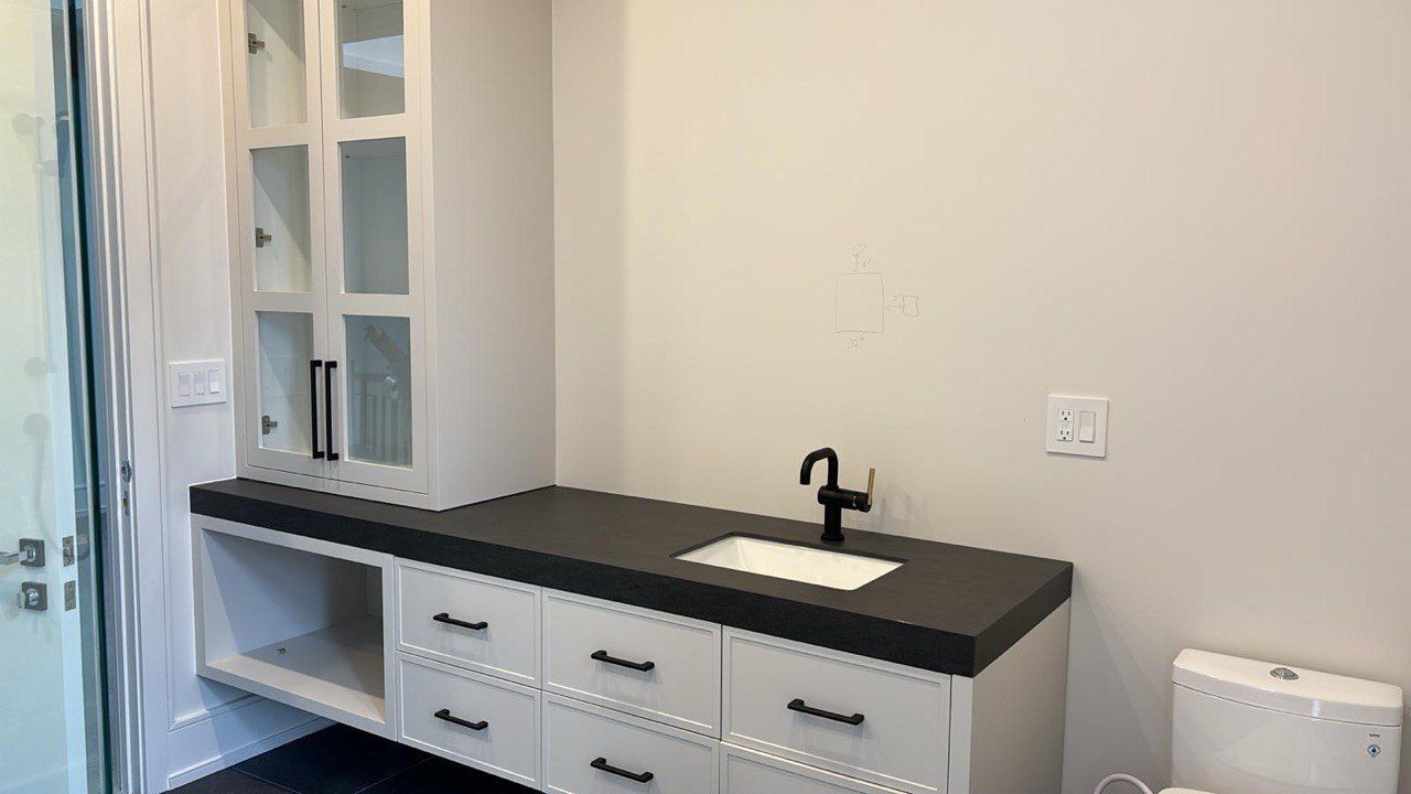 A bathroom with a sink , cabinets , drawers and a toilet.