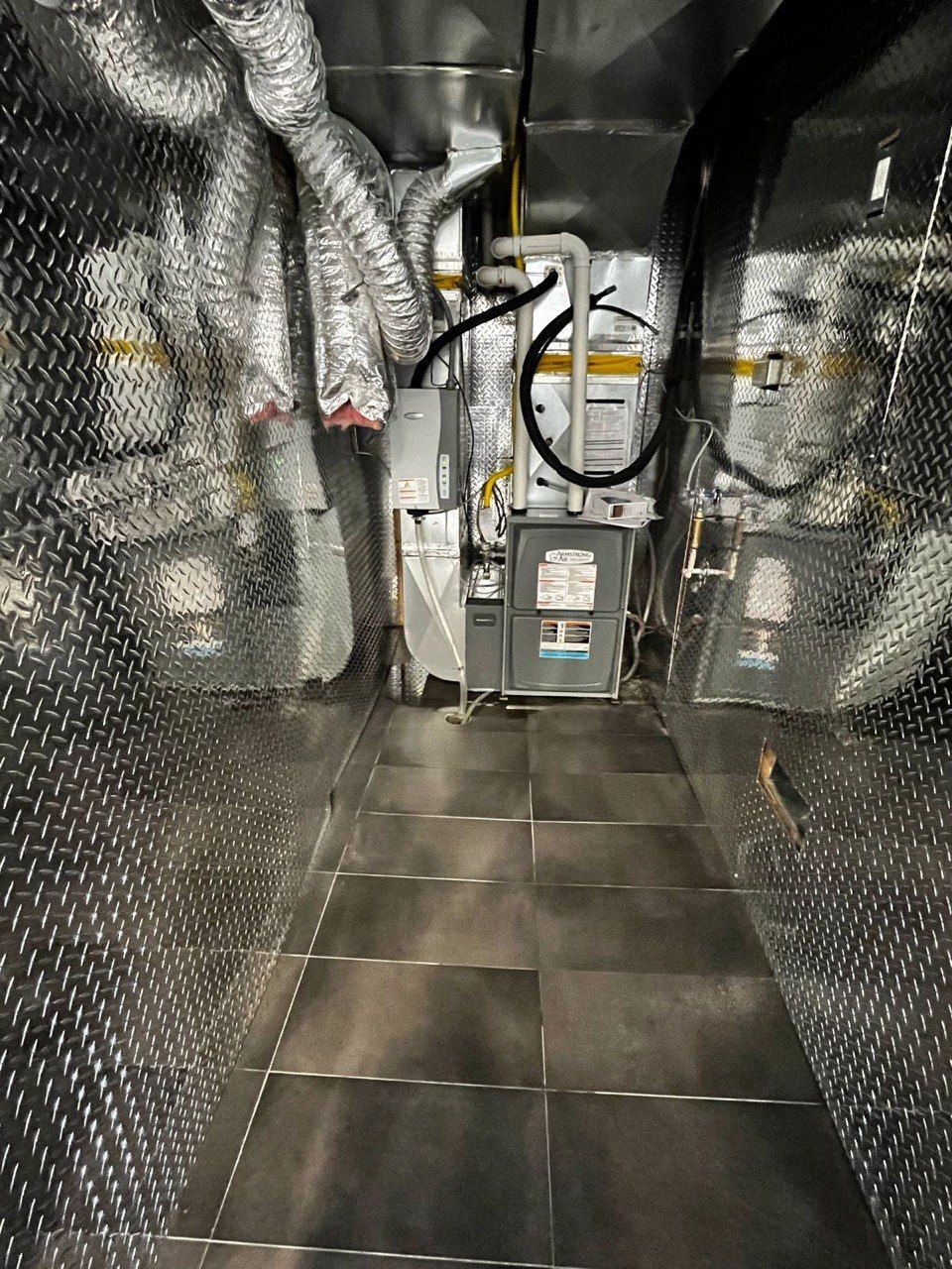 A very long hallway with a lot of pipes hanging from the ceiling.