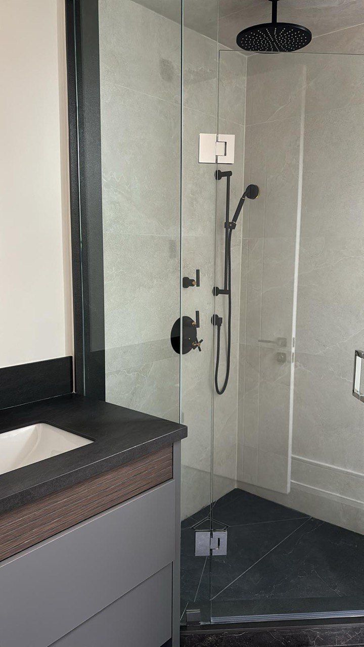 A bathroom with a sink and a shower with a glass door.