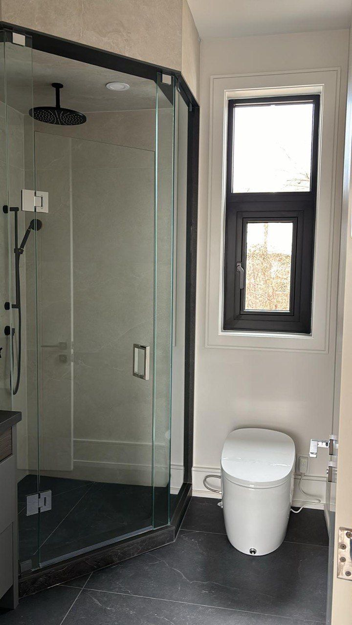 A bathroom with a toilet , shower and window.