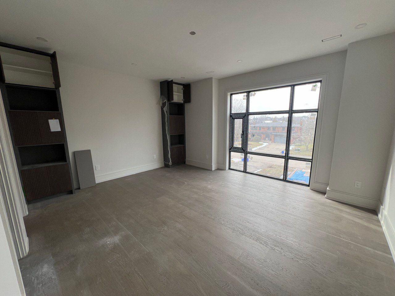 A large empty room with a lot of windows and hardwood floors.