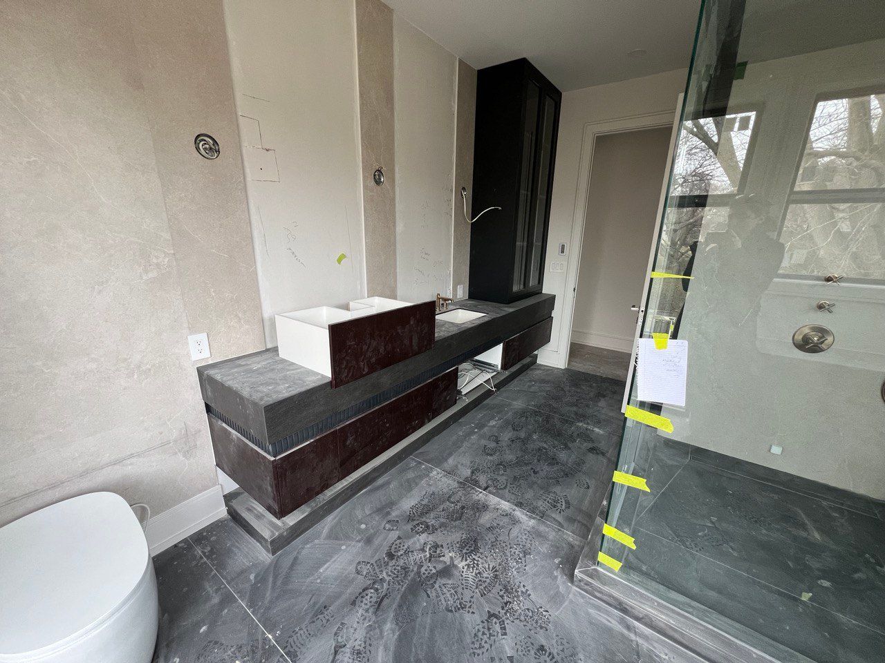 A bathroom with two sinks , a toilet , and a walk in shower.