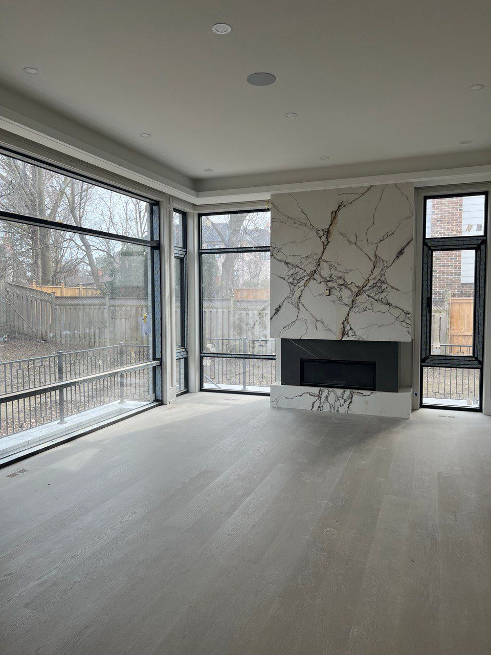 An empty living room with a fireplace and lots of windows.