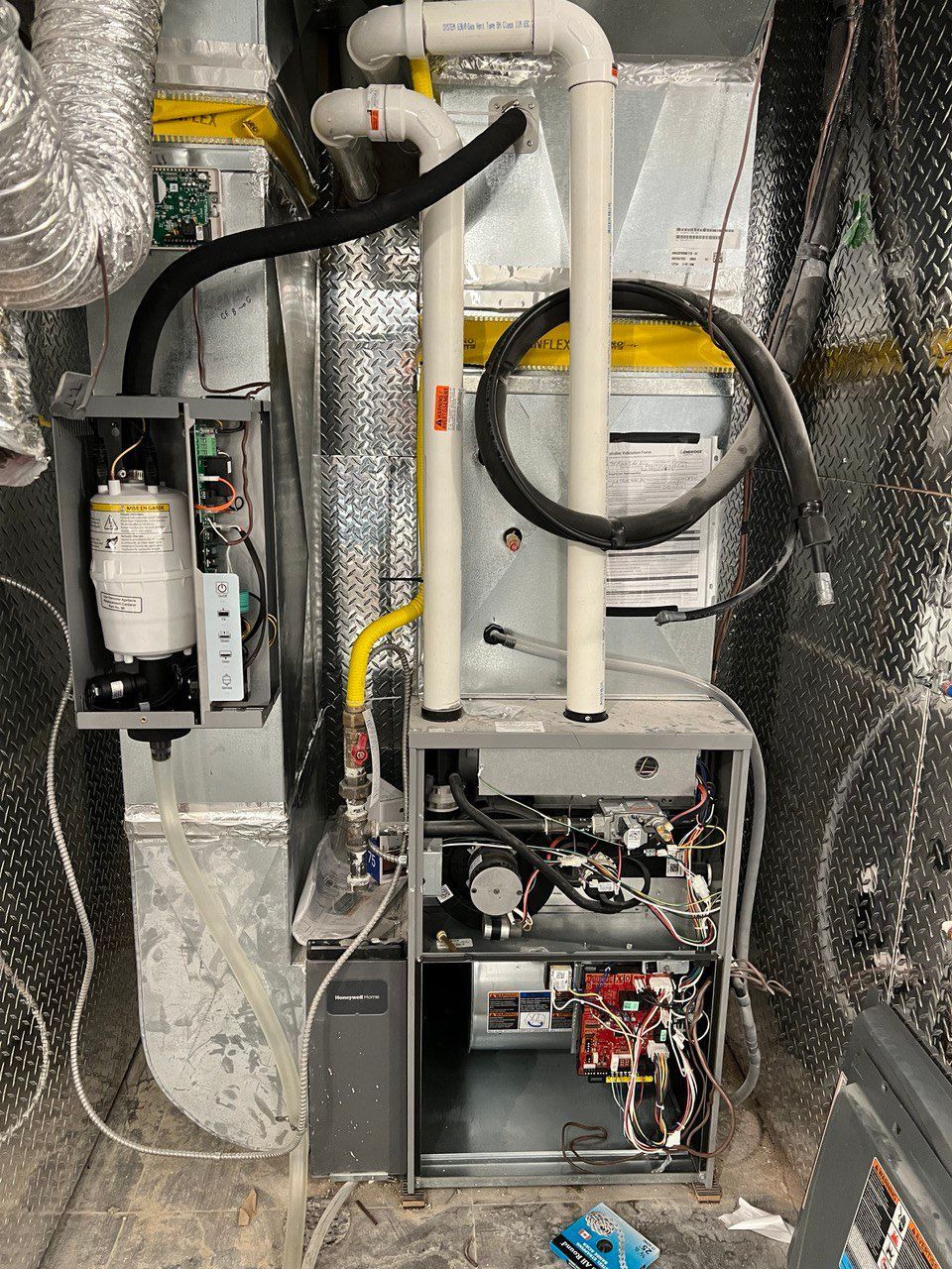 The inside of a heating and cooling system with a lot of wires coming out of it.
