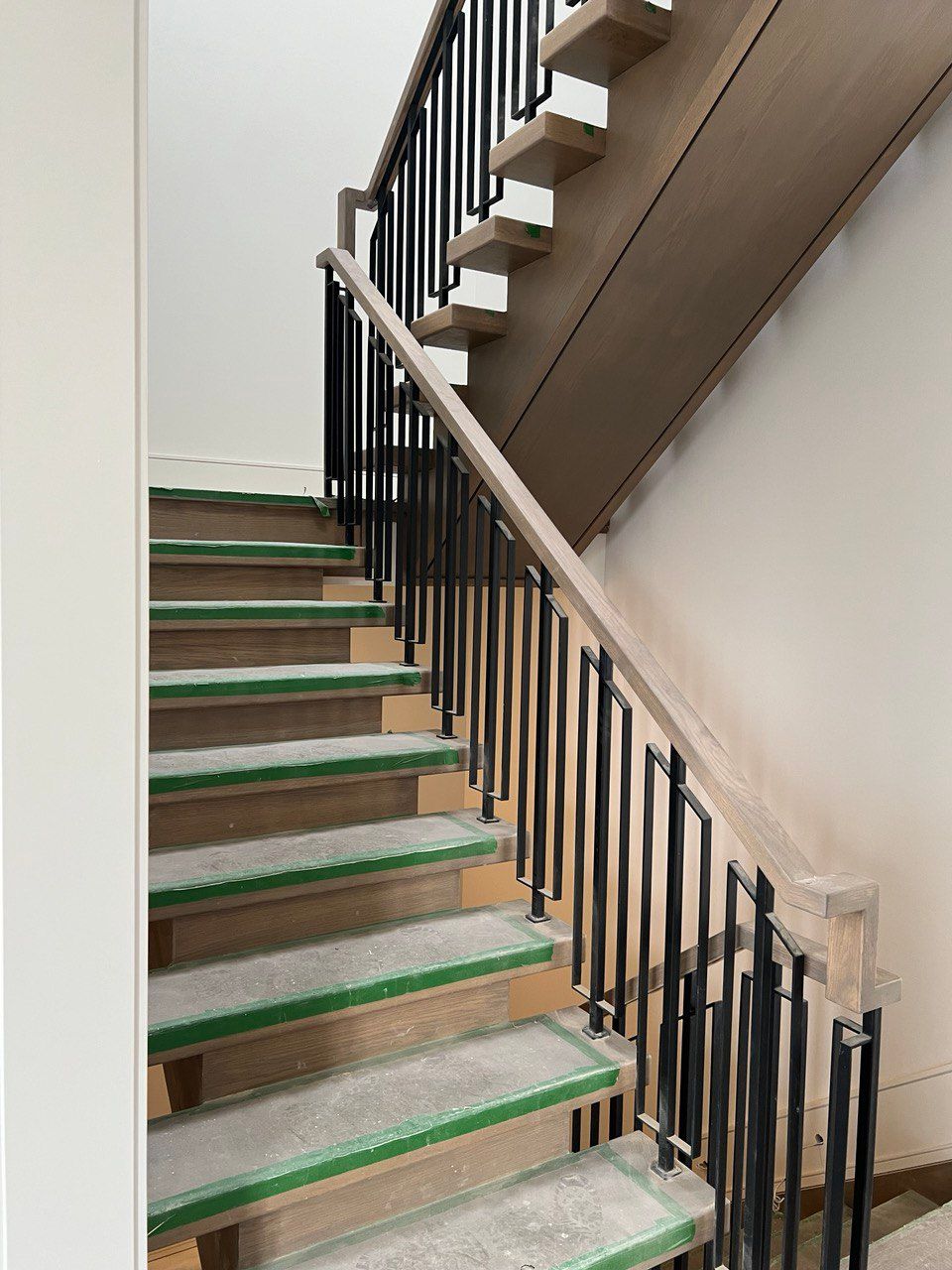 A wooden staircase with green steps and a black railing.