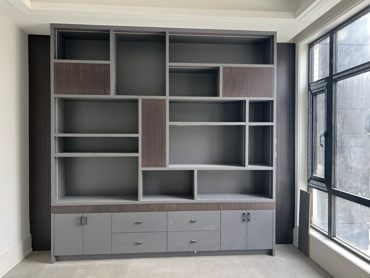 An empty room with a large bookshelf and a window.