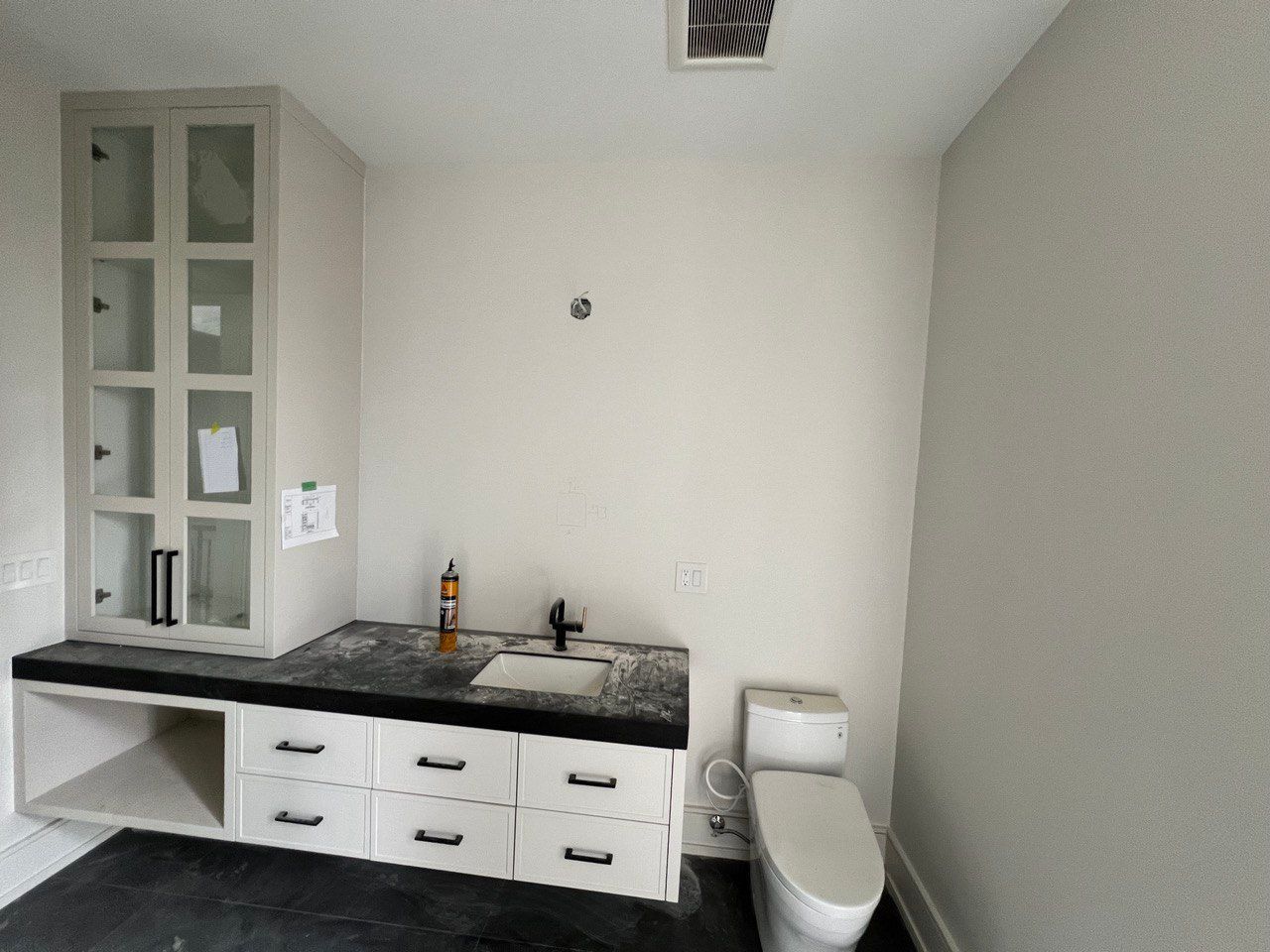 A bathroom with a sink , toilet and cabinets