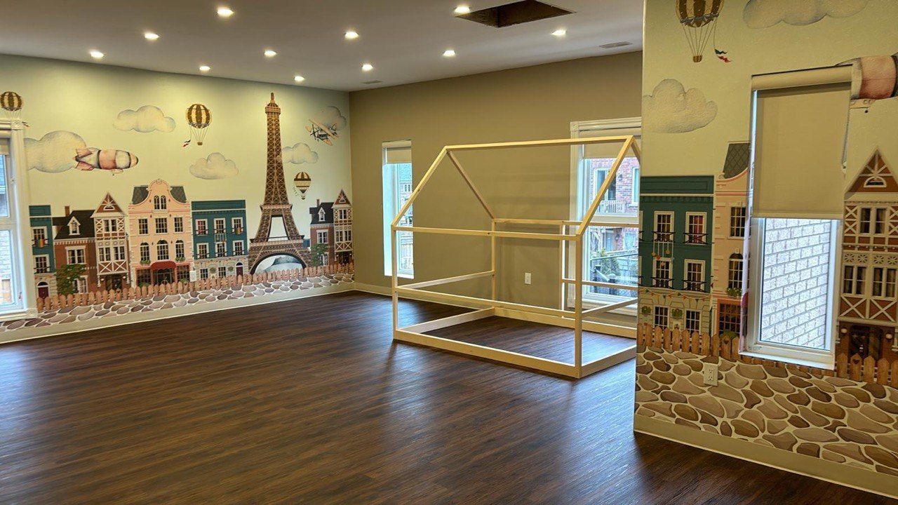 A room with a wooden playhouse and a mural on the wall.