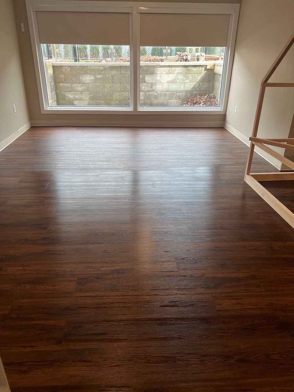 A living room with hardwood floors and a large window.